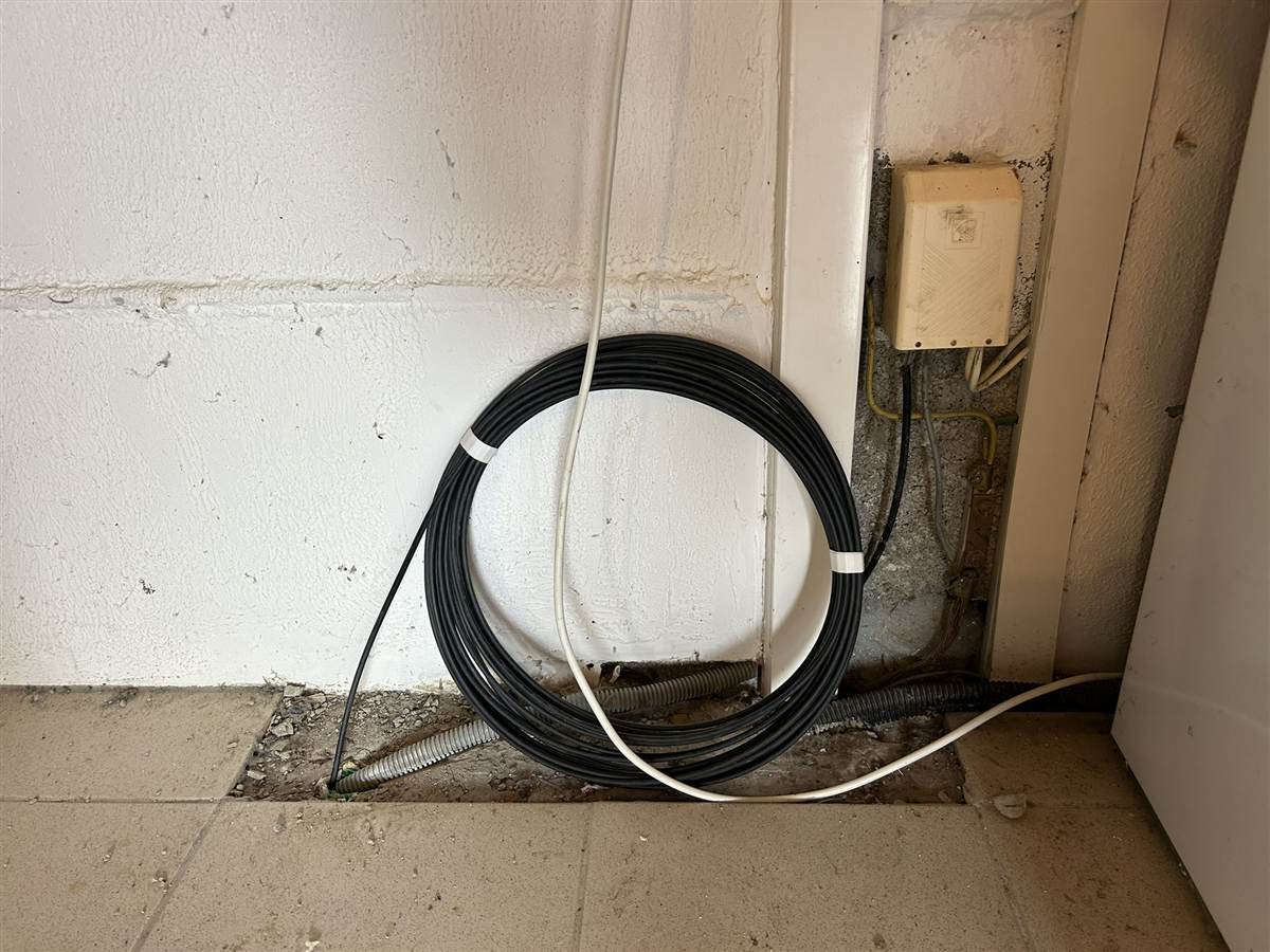 Câble fibre lové en attente à l'intérieur, près d'une ancienne boîte France Telecom