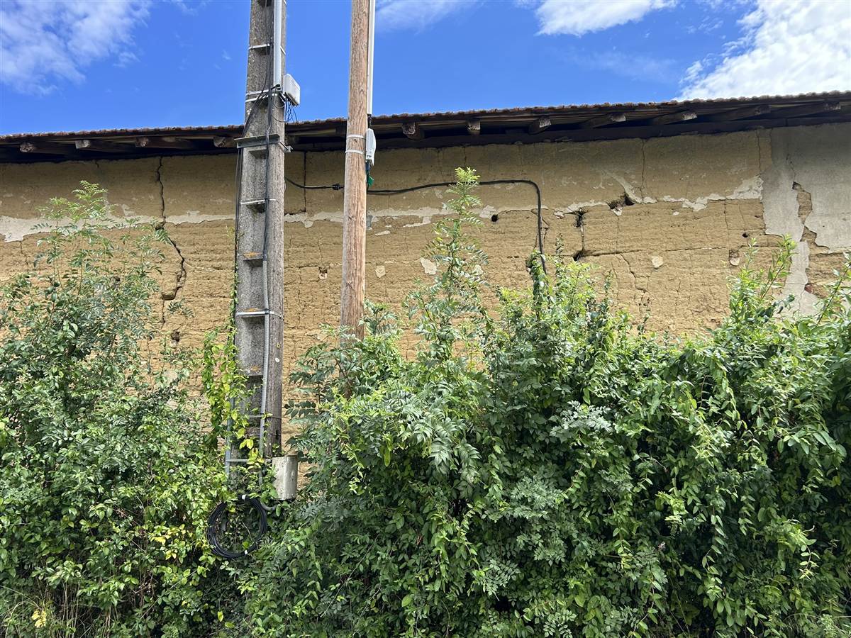 Câble fibre tiré depuis un poteau télécom le long d'un mur en pisé