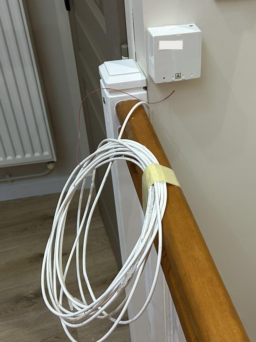 Câble fibre lové et scotché au ruban de masquage sur une rampe d'escalier, avant intervention